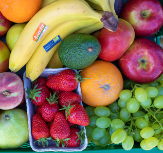 Bunte Auswahl an frischem Obst: Erdbeeren, Bananen, Avocado, Orange, Trauben, Pfirsich, Apfel und Mango, dicht nebeneinander präsentiert.