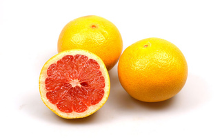 Drei Grapefruits, eine davon halbiert, auf weißem Hintergrund.