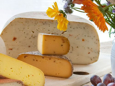 Verschiedene Sorten Bio-Käse auf einem Holzbrett, dekoriert mit Blumen.