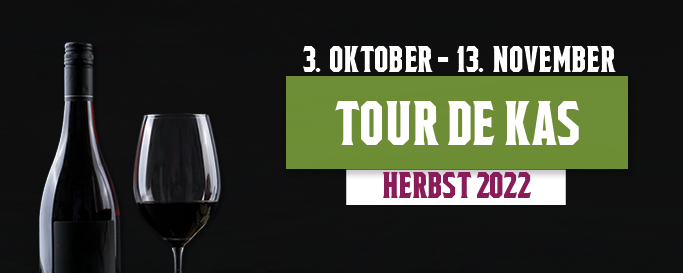 Ein Werbebanner für die "Tour de Kas" im Herbst 2022. Auf einem schwarzen Hintergrund ist eine Flasche Rotwein und ein teilweise gefülltes Weinglas zu sehen. Rechts über dem Wein sind zwei große Banner mit weißer Schrift. Der obere Banner ist schwarz und trägt das Datum "3. OKTOBER - 13. NOVEMBER". Darunter ist ein großer, grüner Banner mit der Aufschrift "TOUR DE KAS", und darunter ein kleinerer, weißer Banner mit dem Text "HERBST 2022".