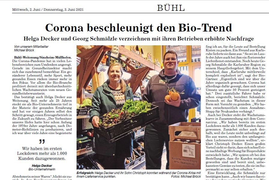  Das Bild zeigt Helga Decker und ihren Sohn Christoph vor einem gut gefüllten Verkaufsregal in einem Bio-Laden. Helga Decker, eine Frau mittleren Alters mit blonden Haaren, hält zwei Kisten mit frischem Salat in der Hand. Ihr Sohn Christoph, ein Mann mit Brille, trägt einen grauen Pullover und hält einen orangen Kürbis. Über dem Foto steht der Titel "Corona beschleunigt den Bio-Trend". Daneben ist ein Zeitungsartikel zu sehen.
