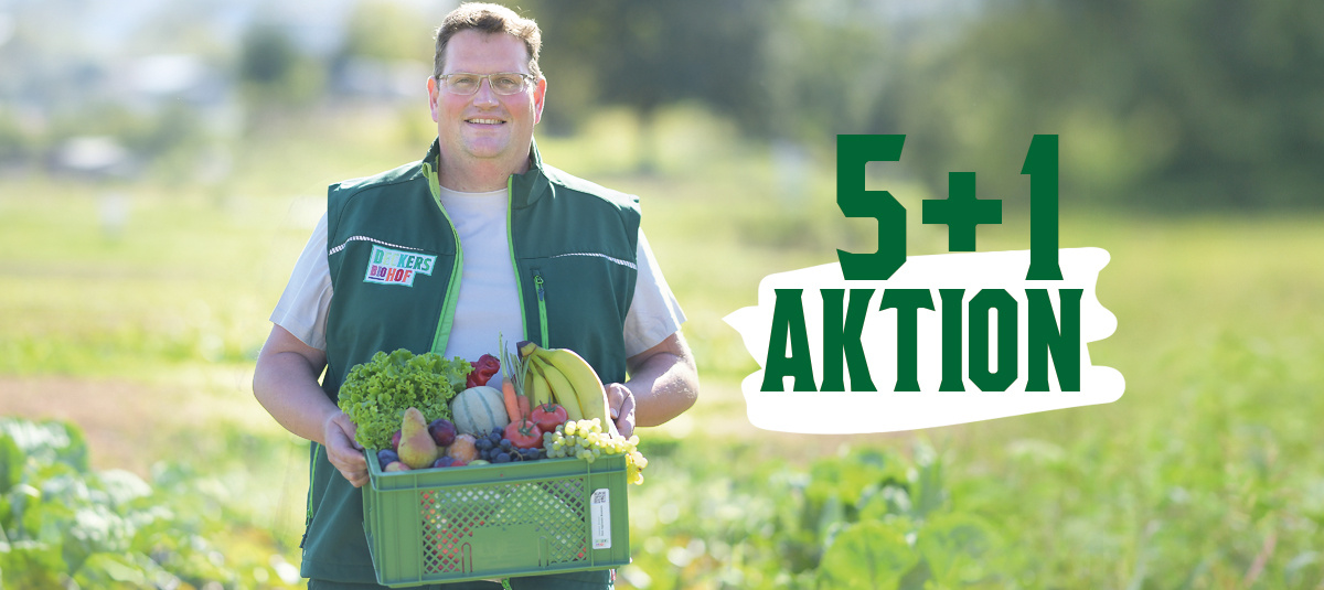 Zwei Mitarbeiterinnen in grünem T-Shirt in einem Bioladen. Die vordere Frau hält eine Packung Weizenmehl in der Hand, im Hintergrund steht die zweite Frau mit einem Einkauf voller Lebensmittel.