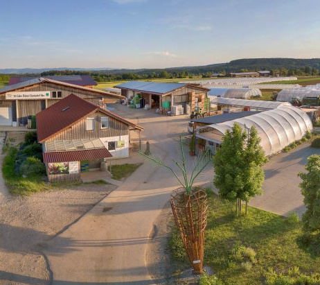 Blick über landwirtschaftliche Gebäude mit großen Gewächshäusern.