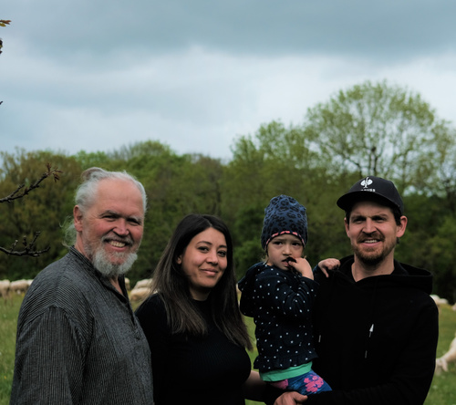 Gruppe von Menschen auf einem Bauernhof, lächelnd in die Kamera.