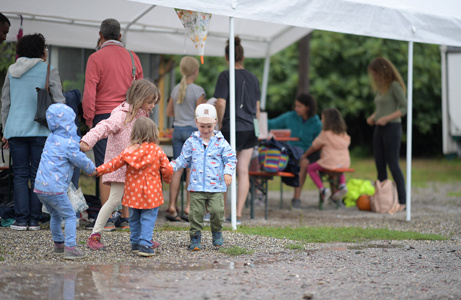 Kinder in Regenjacken schauen neugierig an einem Stand vorbei – familienfreundliche Atmosphäre mit Entdeckungsmöglichkeiten.