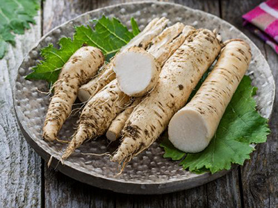 Frischer Meerrettich auf einem Holztisch, teils geschält.