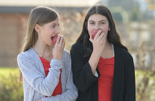 KI generiert: Zwei Mädchen essen Äpfel im Freien.