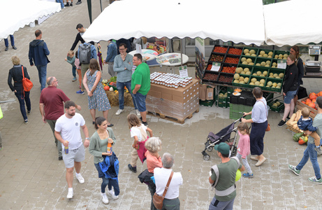 Eine Vogelperspektive zeigt viele Menschen, die auf einem belebten Freiluftmarkt umhergehen und Stände durchsuchen.